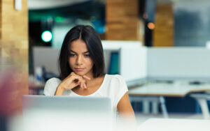 A young girl is reading on her computer.