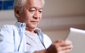 An older man reading an tablet.