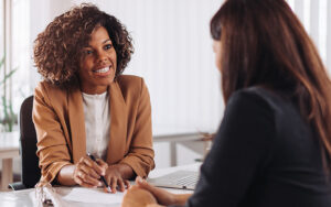 A woman is talking to another person pointing to a piece of paper explaining what's on it.