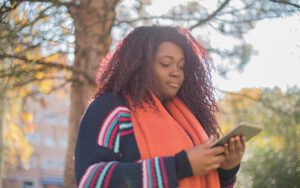 A young girl is outside reading a tablet.