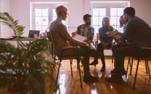 A group of people sitting in a circle talking to one another.