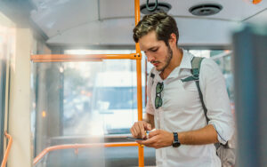 A young man on a bus looking at his phone.