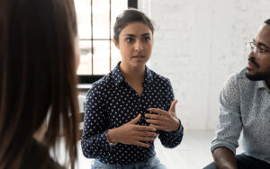 A young woman talking to a group of people.