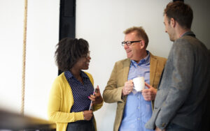 A group of three people laughing and talking to one another