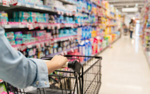 A person pushing a grocery cart in a supermarket.