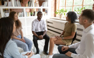 A group of people sitting in a circle talking to one another.