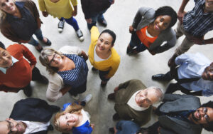 A group of people in colorful clothing are all standing and looking up at the camera.