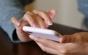 The hands of a person using a touchscreen phone.