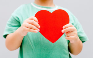 A child in a green tshirt is holding a red hard.